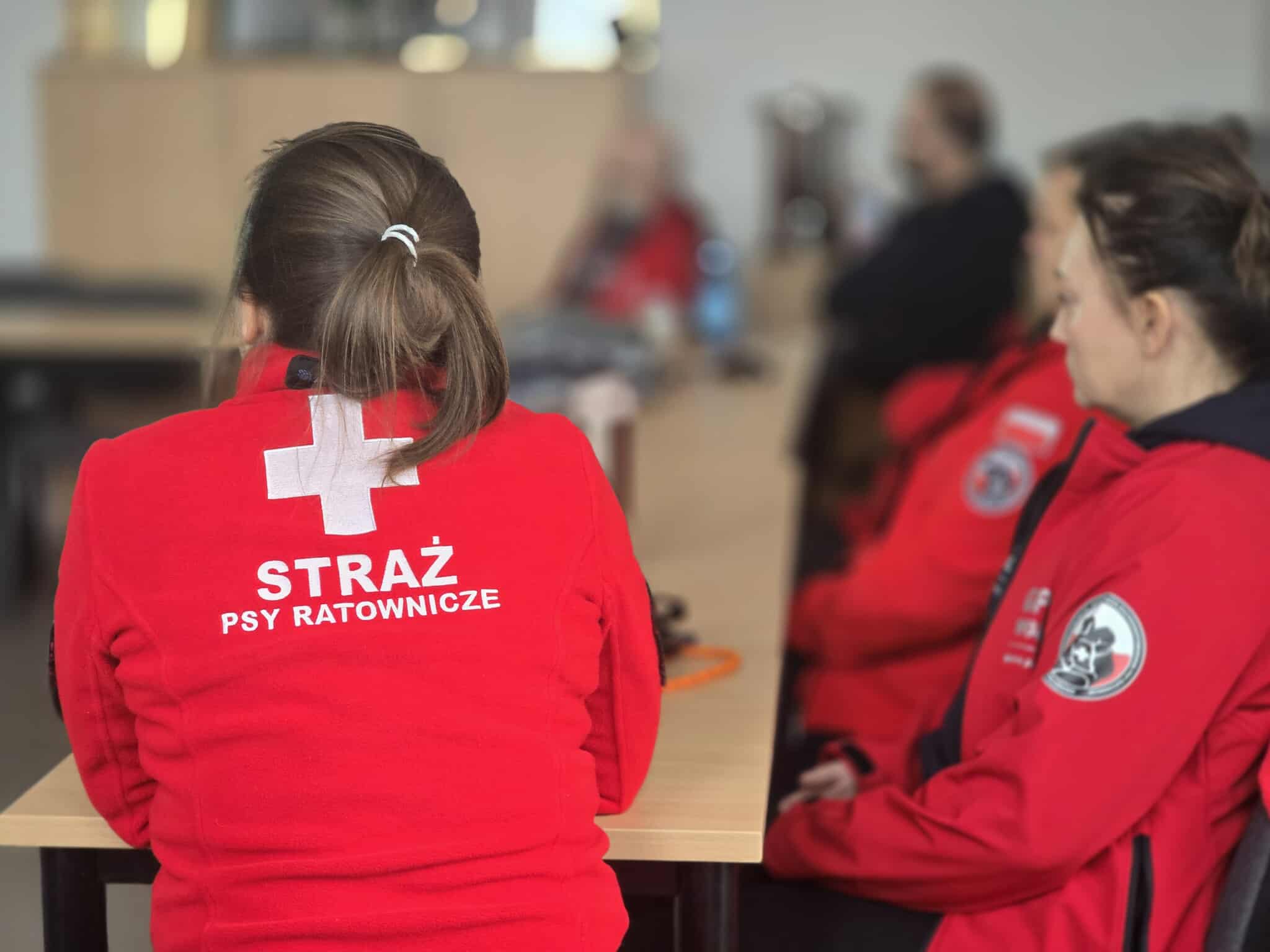 Plecy ratownika- napis Straż- Psy Ratonicze na czerwonej bluzie pożarowej