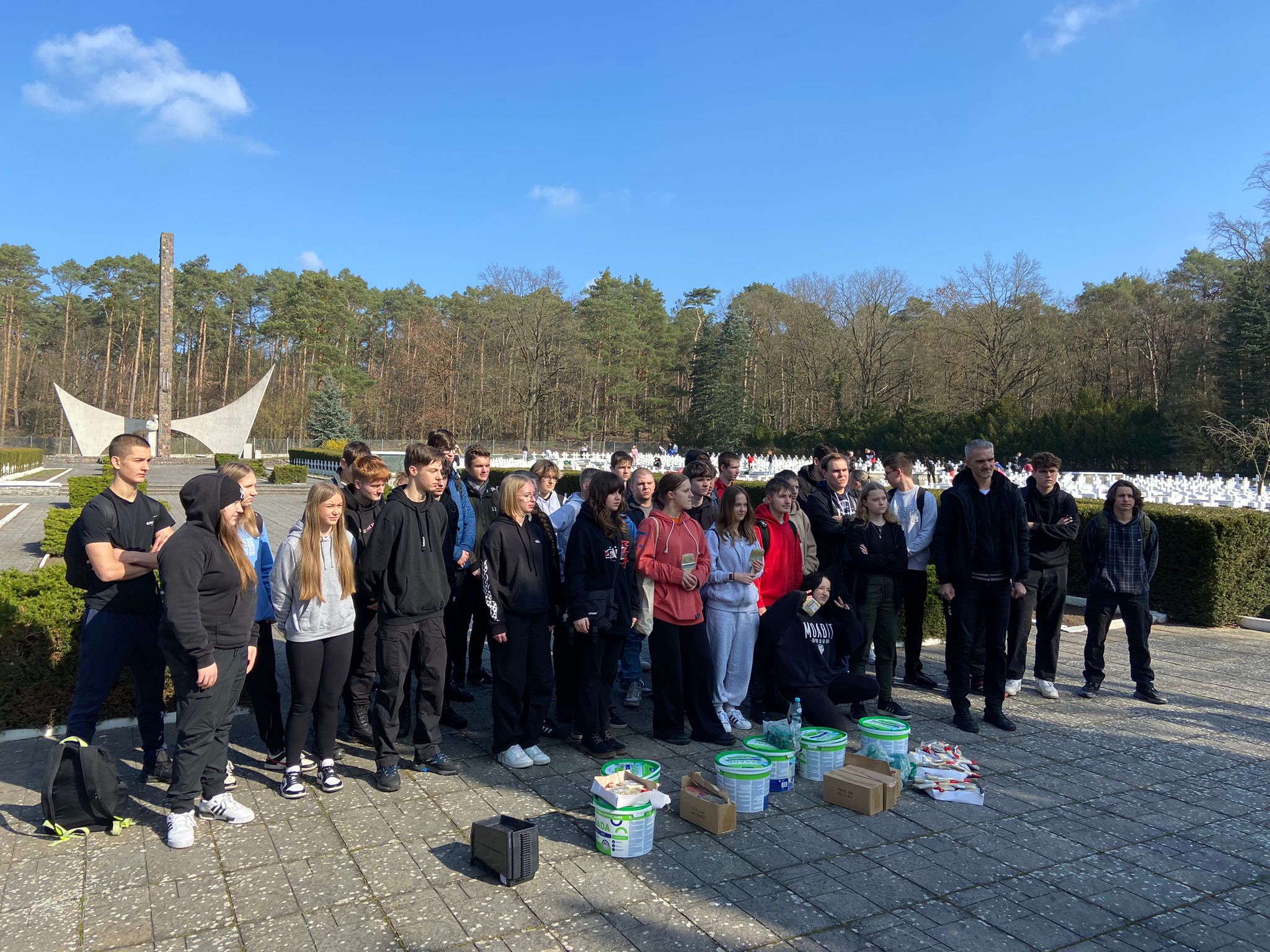 Przystępujemy do sprzątania! Uczniowie na tle cmentarza- zdjęcie grupowe