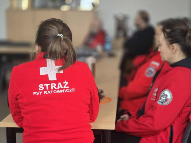 Plecy ratownika- napis Straż- Psy Ratonicze na czerwonej bluzie pożarowej