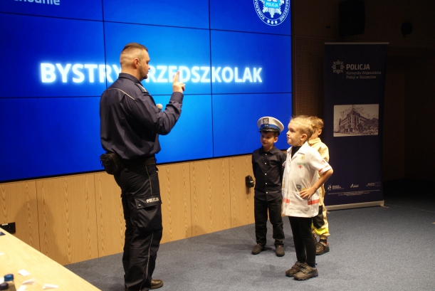 Policjant (po lewej) zadaje pytania trójce uczestników