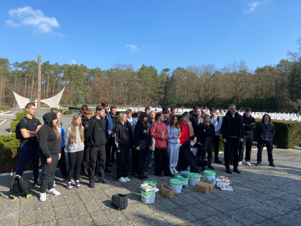 Przystępujemy do sprzątania! Uczniowie na tle cmentarza- zdjęcie grupowe
