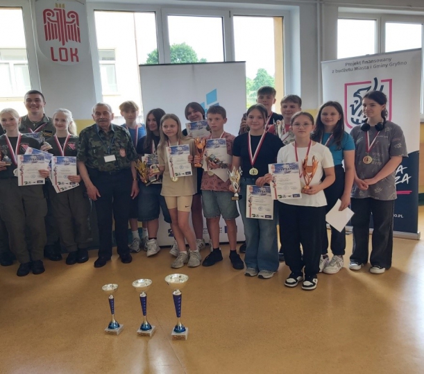 Zdjęcie zbiorowe - zwycięzcy konkursu, na pierwszym planie widoczne puchary.